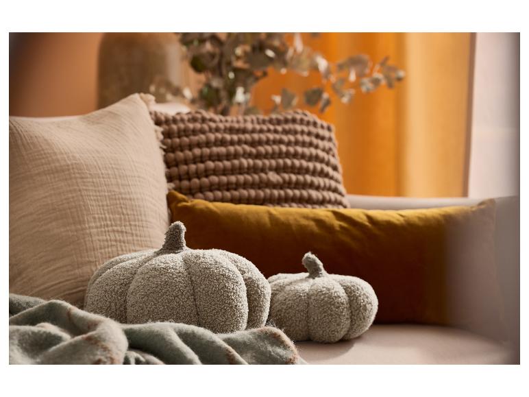 Kuschelige graue Kürbisse aus Plüsch auf einem Sofa mit beige und braunen Kissen.