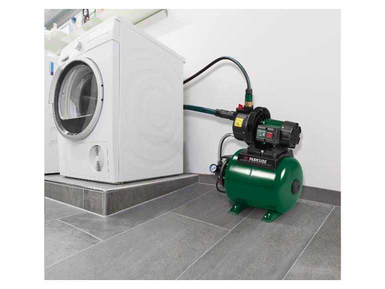 Grüne Hauswasserpumpe, die an eine weiße Waschmaschine in einem Waschraum angeschlossen ist.