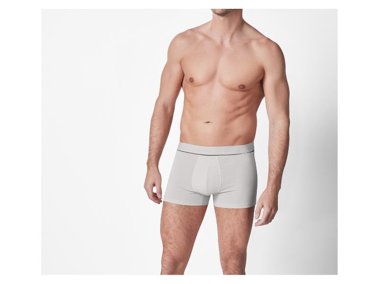 Ein Mann trägt weiße Boxershorts vor weißem Hintergrund.