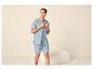 Lächelnder Mann in hellblauem Sommerpyjama, Kurzarmhemd und Shorts.