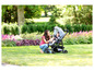 Eine Mutter schiebt ein Baby im Graco-Kinderwagen über den Rasen im Garten.