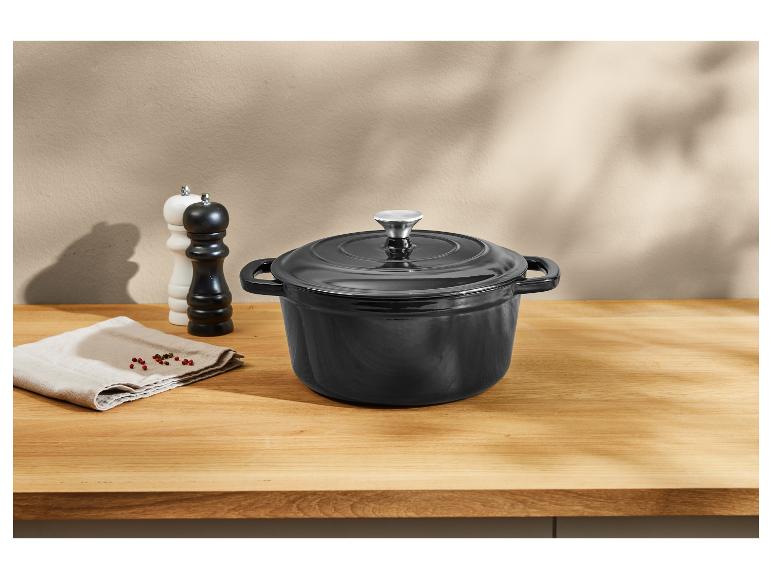 Schwarzer gusseiserner Topf auf einer Holztheke.