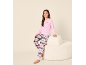 Mädchen in rosa Langarmshirt mit Croissant-Grafik und rosa karierter Pyjamahose, sitzt auf einem cremefarbenen Hocker.