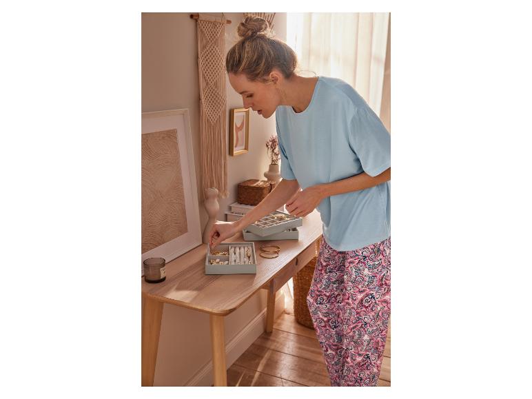 Eine Frau sortiert Schmuck in einer blauen Schmuckschatulle.