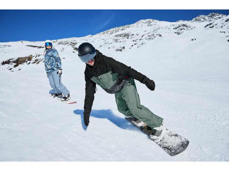 Zwei Snowboarder auf einer Bergpiste in Wintersportbekleidung.