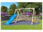 Holzspielplatz mit blauer Rutsche und roten Schaukeln in einer Gartenumgebung.