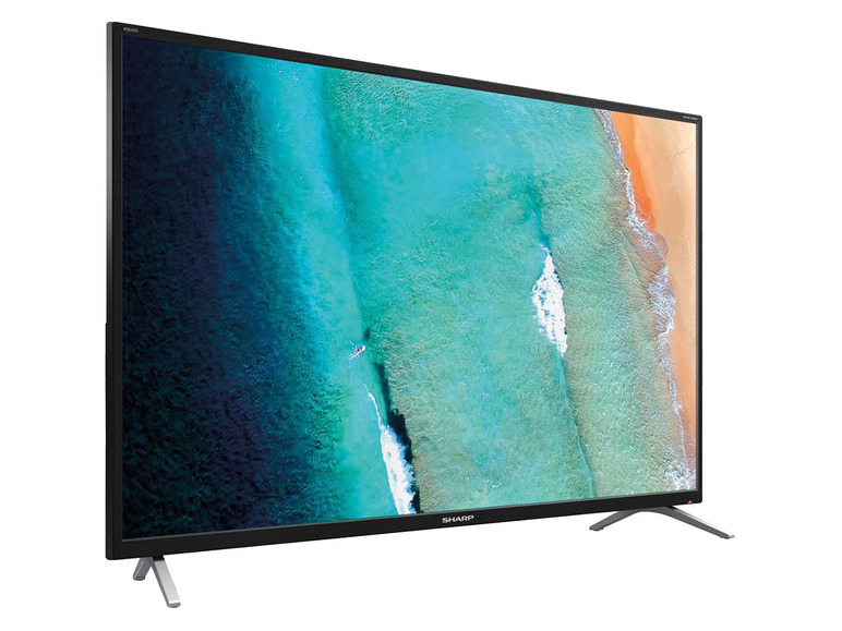 Ein schwarzer Sharp Aquos Fernseher mit einem Strandbild auf dem Bildschirm.