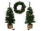 Zwei künstliche Weihnachtsbäume in Töpfen und ein Weihnachtskranz, alle beleuchtet.