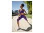 Frau in lila Sport-BH und Capri-Leggings dehnt sich draußen.