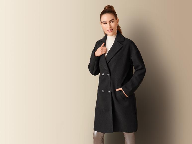 Eine Frau in einem schwarzen Mantel und einer Hose