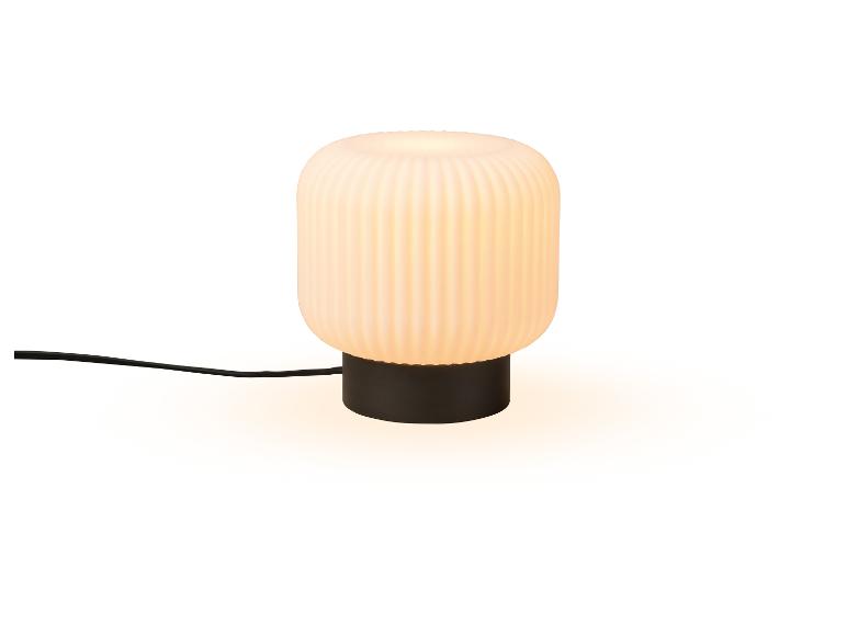 Weiße Tischlampe mit geripptem Schirm und schwarzem Sockel, mit sichtbarem Kabel.