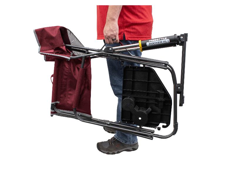Ein Mann trägt einen zusammenklappbaren Freestyle Rocker XL Campingstuhl.