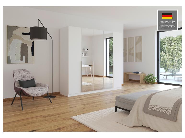 Modernes Schlafzimmer mit weißem Spiegelschrank, Sessel und Bett, 'made in Germany'.