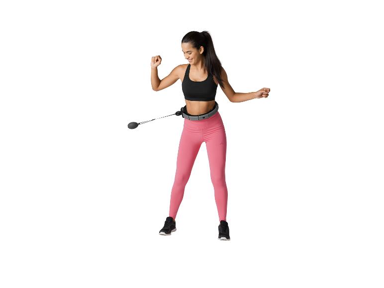 Lächelnde Frau mit einem Smart Hula Hoop und pinken Leggings.