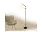Moderne schwarze Stehlampe beleuchtet einen grauen Sessel in minimalistischem Interieur.