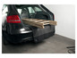 Eine Holzleiter im Kofferraum eines Autos, geschützt durch eine schwarze Stoßfängerabdeckung.