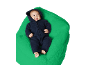 Baby in dunkelblauem Overall liegt auf einem grünen Sitzsack.