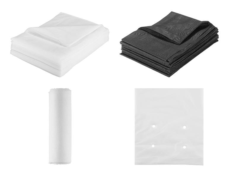 Stapel weißer und schwarzer Vliesstoffe, eine Rolle Papier und ein Plastikbeutel.