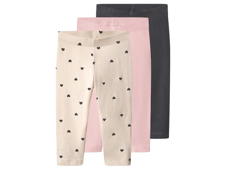 Drei Paar Kinderleggings: eine beige mit schwarzen Herzen, eine rosa und eine dunkelgrau.