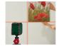 Ein Laser-Nivelliergerät projiziert Kreuzlinien an eine Wand, während Hände ein Bild mit roten Blumen platzieren.