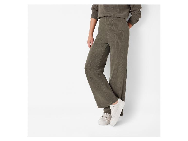 Ein Model trägt eine grüne Cordhose und weiße Sneaker.