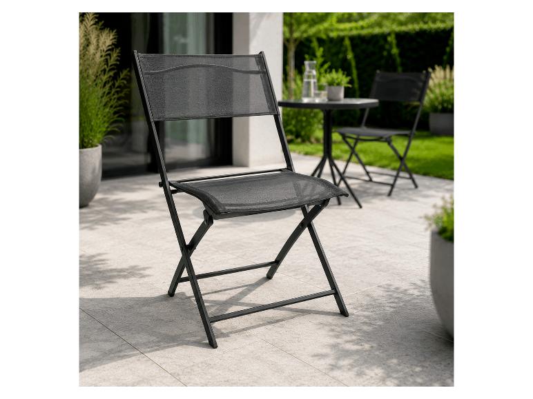 Schwarzer Klapp-Gartenstuhl auf einer Terrasse mit einer Gartenmöbelgarnitur im Hintergrund.