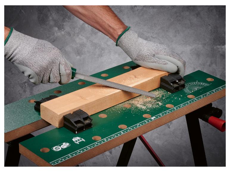 Eine Hand, die eine Feile auf einem Holzbrett auf einem Werktisch verwendet