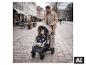 Ein Vater schiebt sein Kind in einem beigen BABYGO Evolution 3in1 Kinderwagen auf einer gepflasterten Straße. [KI-generiertes Bild]
