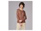 Frau in braunem Langarmshirt und hellbeiger Hose, zur Seite blickend.
