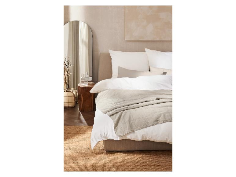 Modernes Schlafzimmer mit Bett, Nachttisch aus Holz, Spiegel und Jute-Teppich.