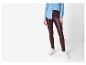 Frau in Jeanshemd und bordeauxroten Leggings mit weißen Sneakern.