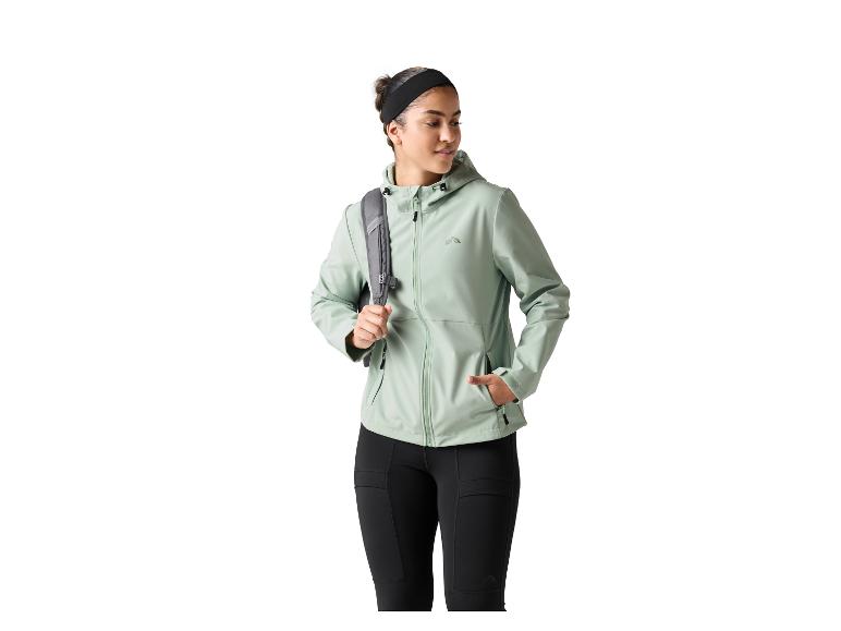 Frau in hellgrüner Jacke und schwarzen Leggings, mit grauem Rucksack.