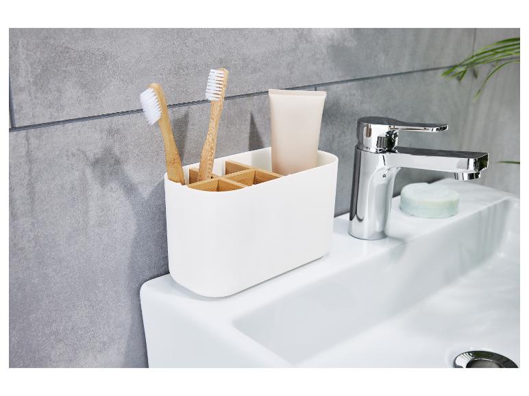 Ein weißer Badezimmerorganizer mit zwei Zahnbürsten und einer Tube Zahnpasta.