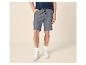 Mann in blauem T-Shirt und grauen Shorts mit Kordelzug, weißen Sneakern.