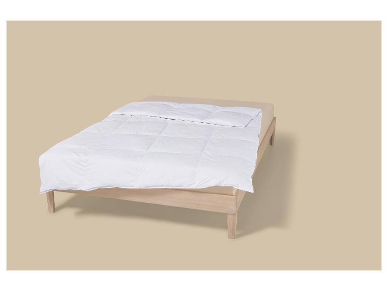 Bett mit Holzrahmen und weißer Bettdecke auf beigem Hintergrund.