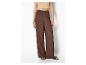 Frau in hellem Top und brauner weiter Hose mit Sandalen.