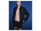 Mann in schwarzem offenem Hoodie und schwarzen Boxershorts mit Aufschrift, vor blauem Hintergrund.