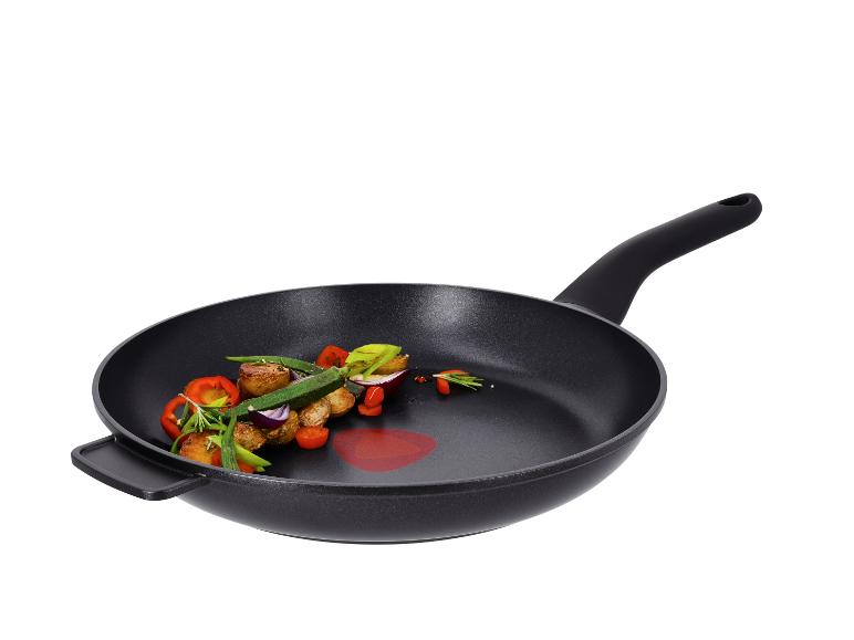 Schwarze Bratpfanne mit geröstetem Gemüse, darunter Kartoffeln, Paprika und Zwiebeln.