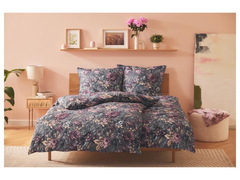 Ein Bett mit floral bedruckter Bettwäsche in einem Schlafzimmer mit rosa Wänden.