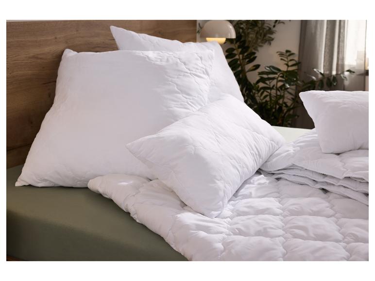 Bett mit weißen Bettdecken und Kissen auf einer grünen Matratze.