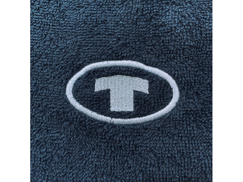 Gesticktes T-Logo in einem Oval auf dunkelblauem Frotteestoff.