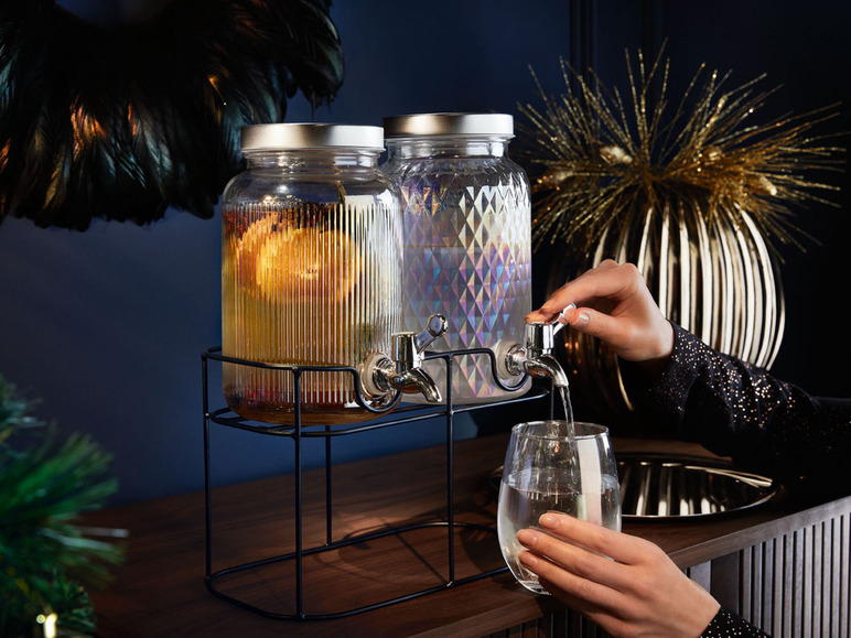 Zwei Glaskaraffen mit Hahn, gefüllt mit Getränken, auf einem Holztisch.