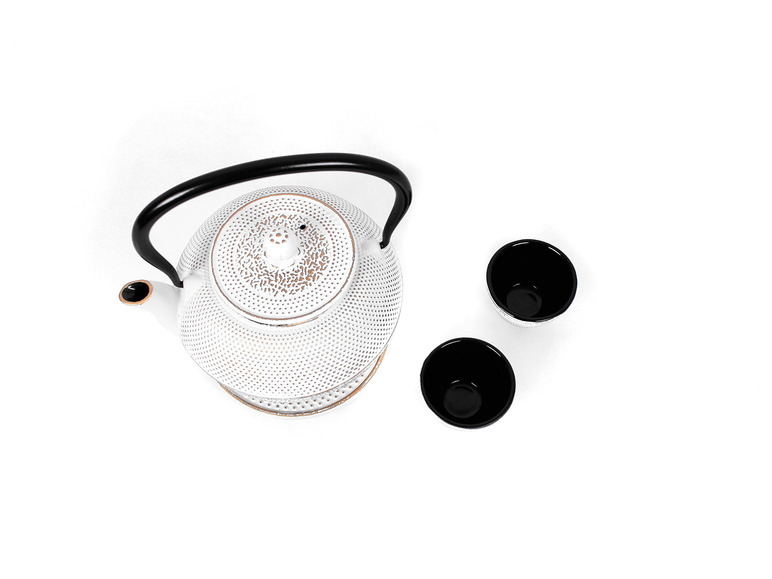 Weiße Teekanne mit zwei schwarzen Tassen