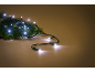 Weiße LED-Weihnachtsbeleuchtung auf einem grünen Tannenzweig, auf warmbraunem Hintergrund.