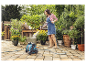 Eine Frau gießt Topfpflanzen mit einem Gardena Gartenschlauch.