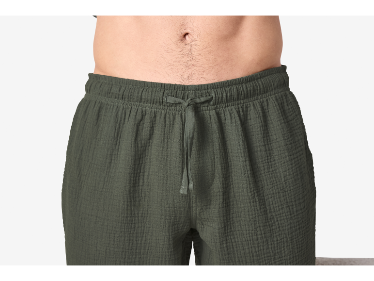 Nahaufnahme eines Männeroberkörpers in dunkelgrünen, gekreppten Baumwollshorts mit Kordelzug