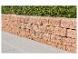 Stützmauer aus Betonblöcken mit einer grünen Hecke im Hintergrund und Terrassenplatten.
