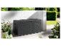 Eine schwarze Aufbewahrungsbox im Rattan-Look in einem Garten.