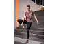 Frau in lila Top und schwarzen Leggings macht Yoga auf einer Matte.
