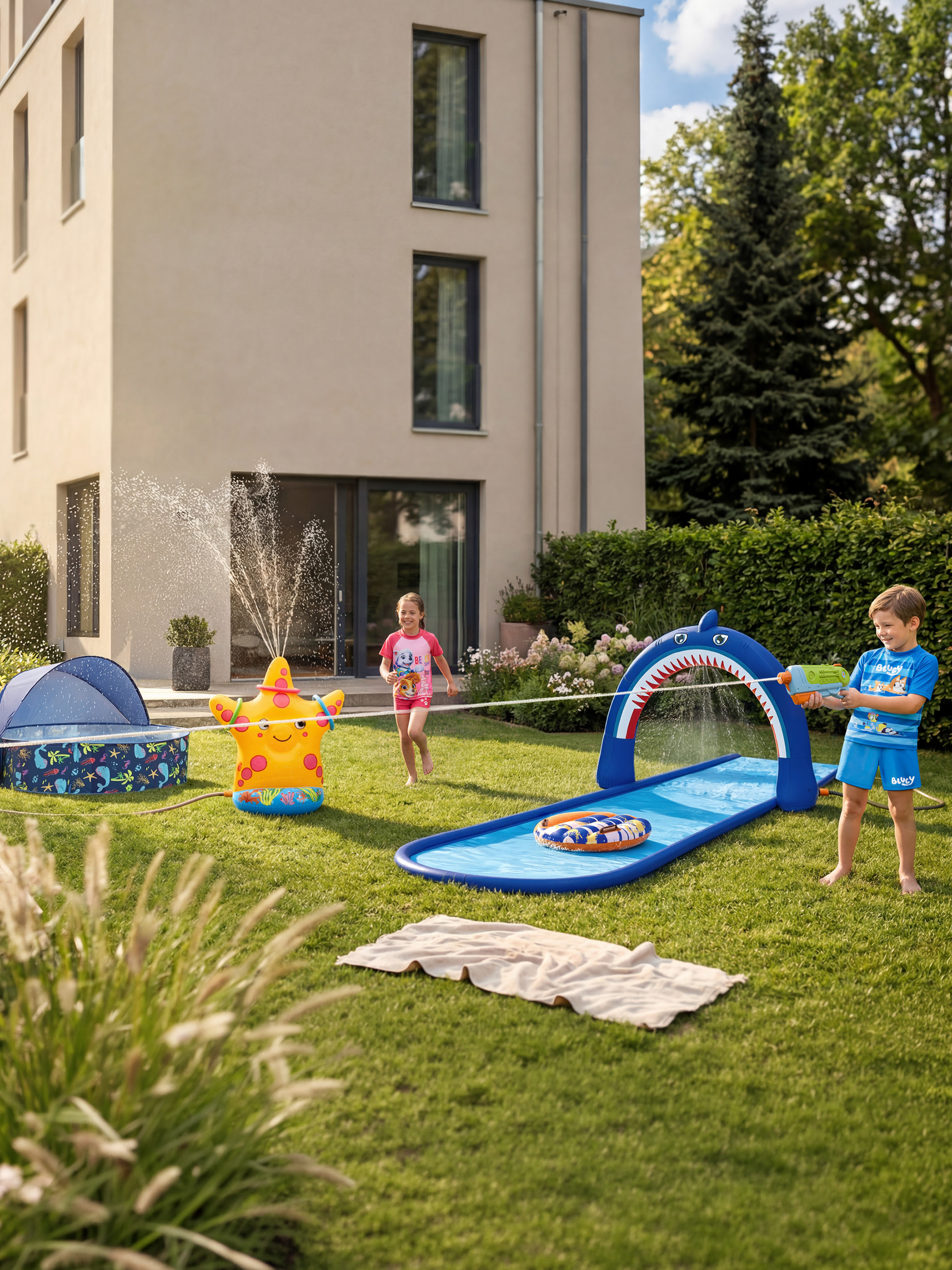 Kinder spielen mit einem Seestern-Gartensprenger und einer Hai-Wasserrutsche.
